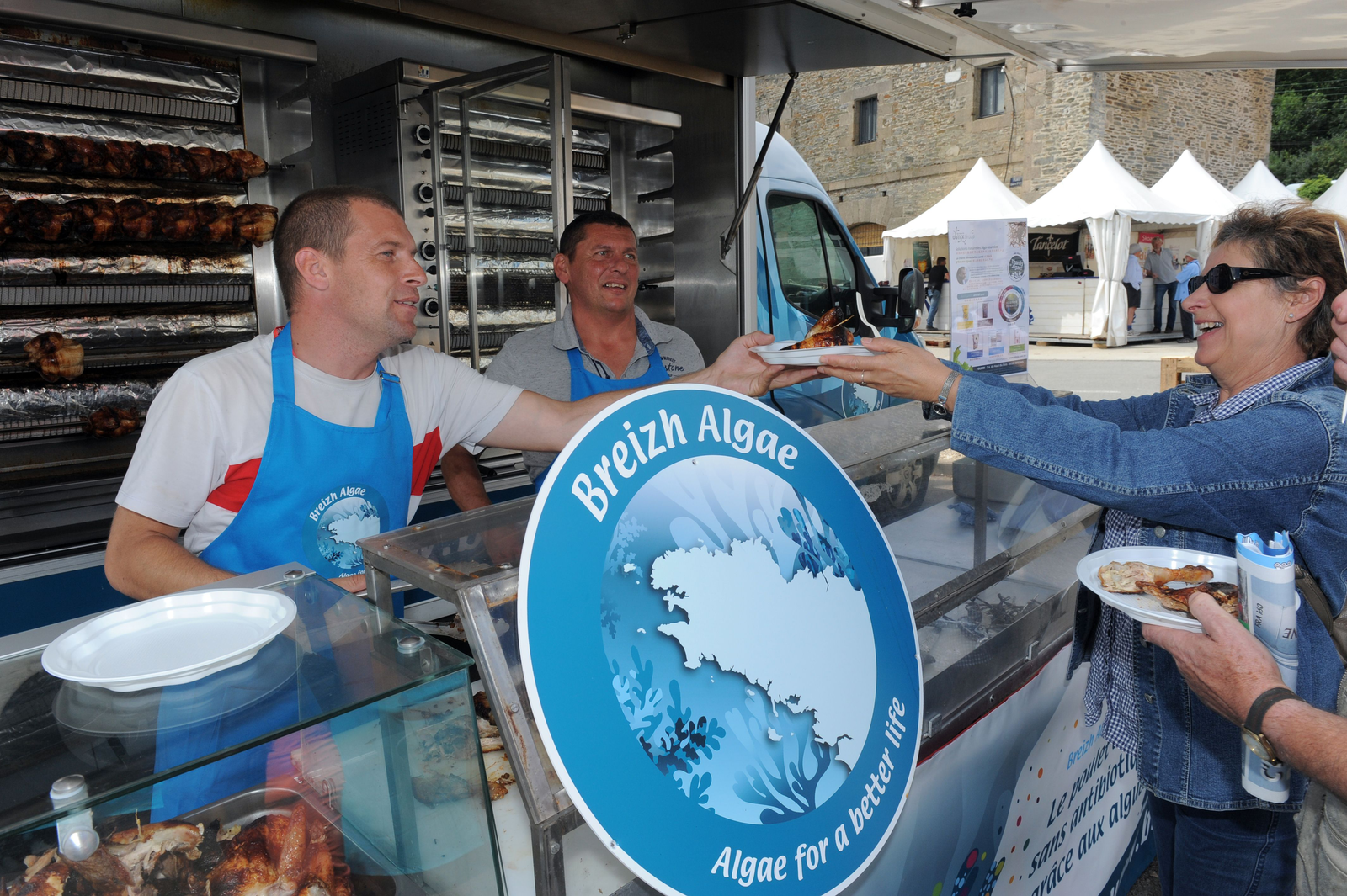 France's Aurelien Leclaire (L) of Breizh Algae Invest, and French rotisserie chef Sebastien Forestier (C) offer roasted antibiotic-free and seaweed-fed chicken to tourists in Morlaix, western France. Breizh Algae Invest, the Investment fund of marine biotechnology specialist Olmix, raises antibiotic-free and seaweed fed chickens. [Photo: ANP]